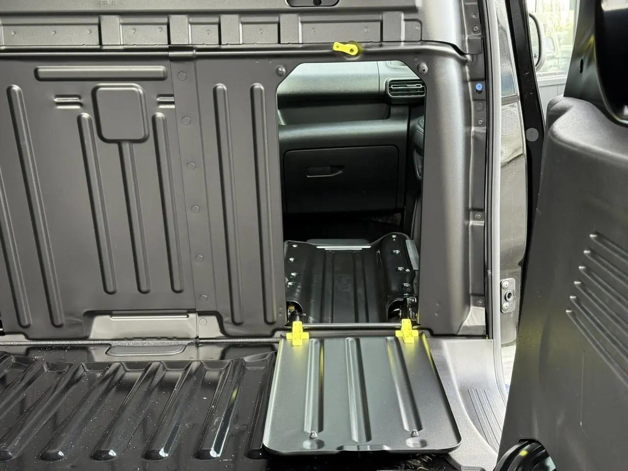 Vue intérieure du coffre du Citroën Berlingo Van 2025 noir Perla avec banquette passager rabattue et tablette écritoire visible.