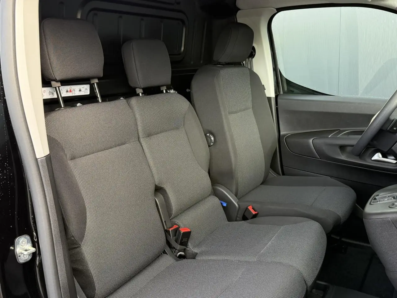 Intérieur du Citroën Berlingo Van 2025, vue latérale des sièges avant gris foncé avec banquette passager double.
