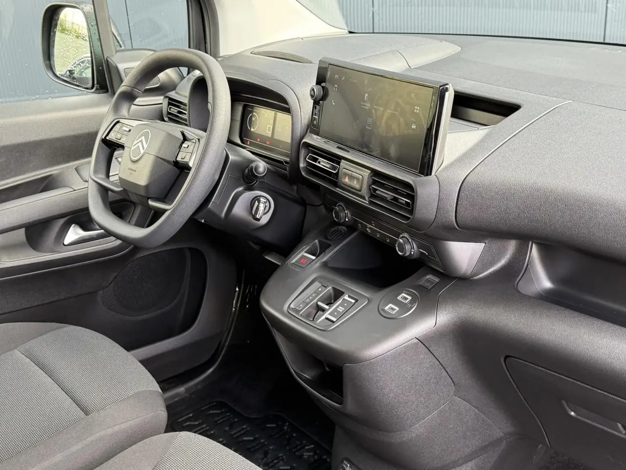 Vue intérieure côté conducteur du Citroën Berlingo 2025 avec tableau de bord noir et écran tactile central.