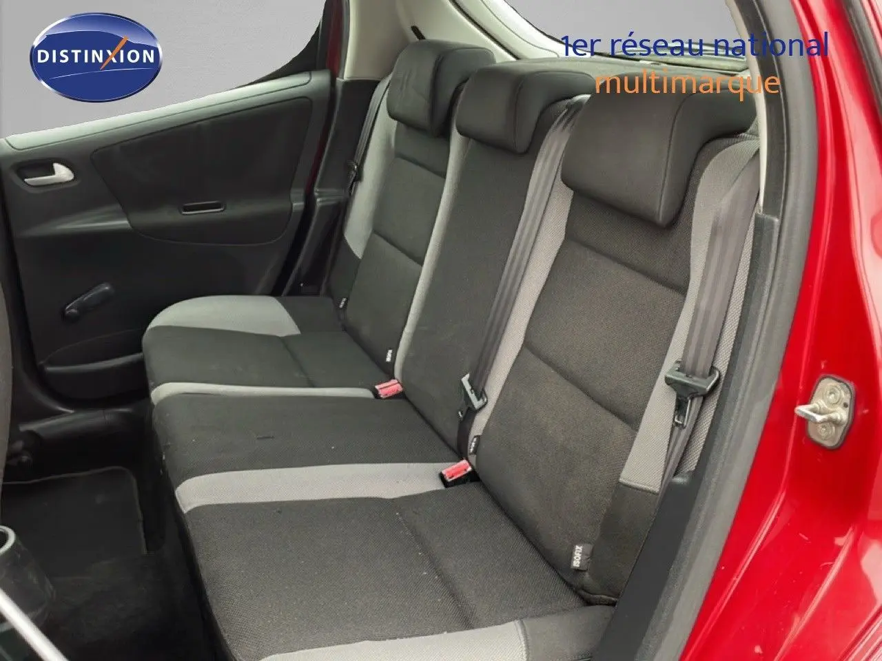 Vue intérieure côté droit sur la banquette arrière en tissu noir et gris d'une Peugeot 207 rouge métallisé 5 portes.