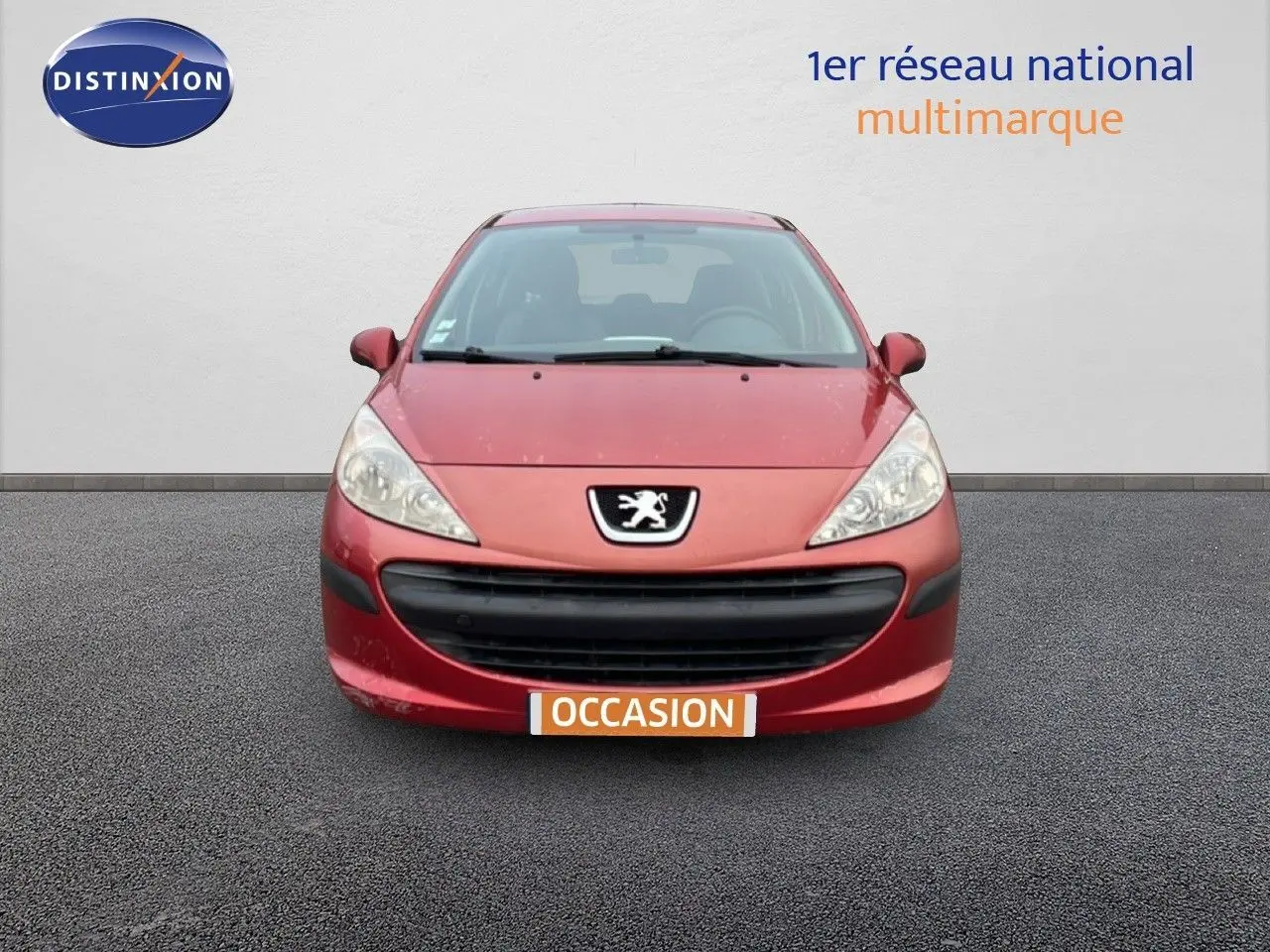 Vue avant d'une Peugeot 207 rouge métal de 2009 avec calandre noire et logo lion bien visible.