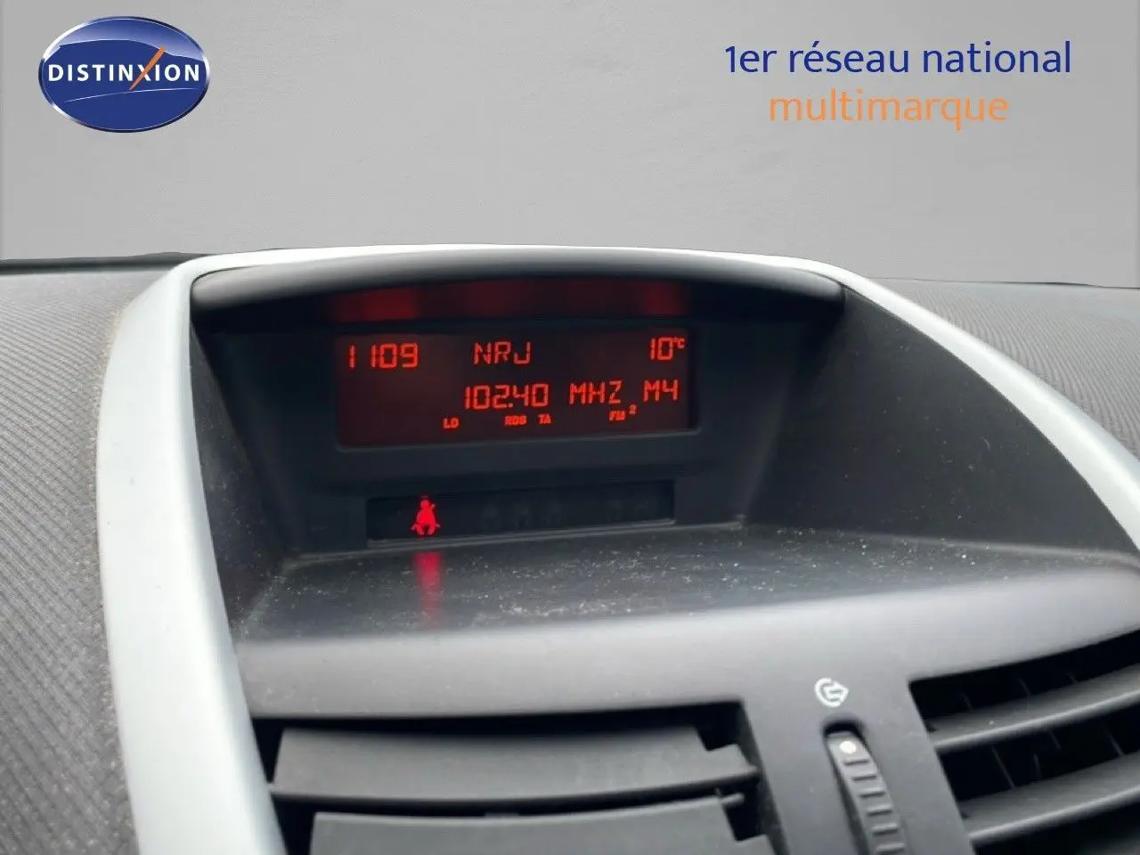 Tableau de bord de Peugeot 207 rouge métal 2009, affichage radio et température, vue intérieure centrée.