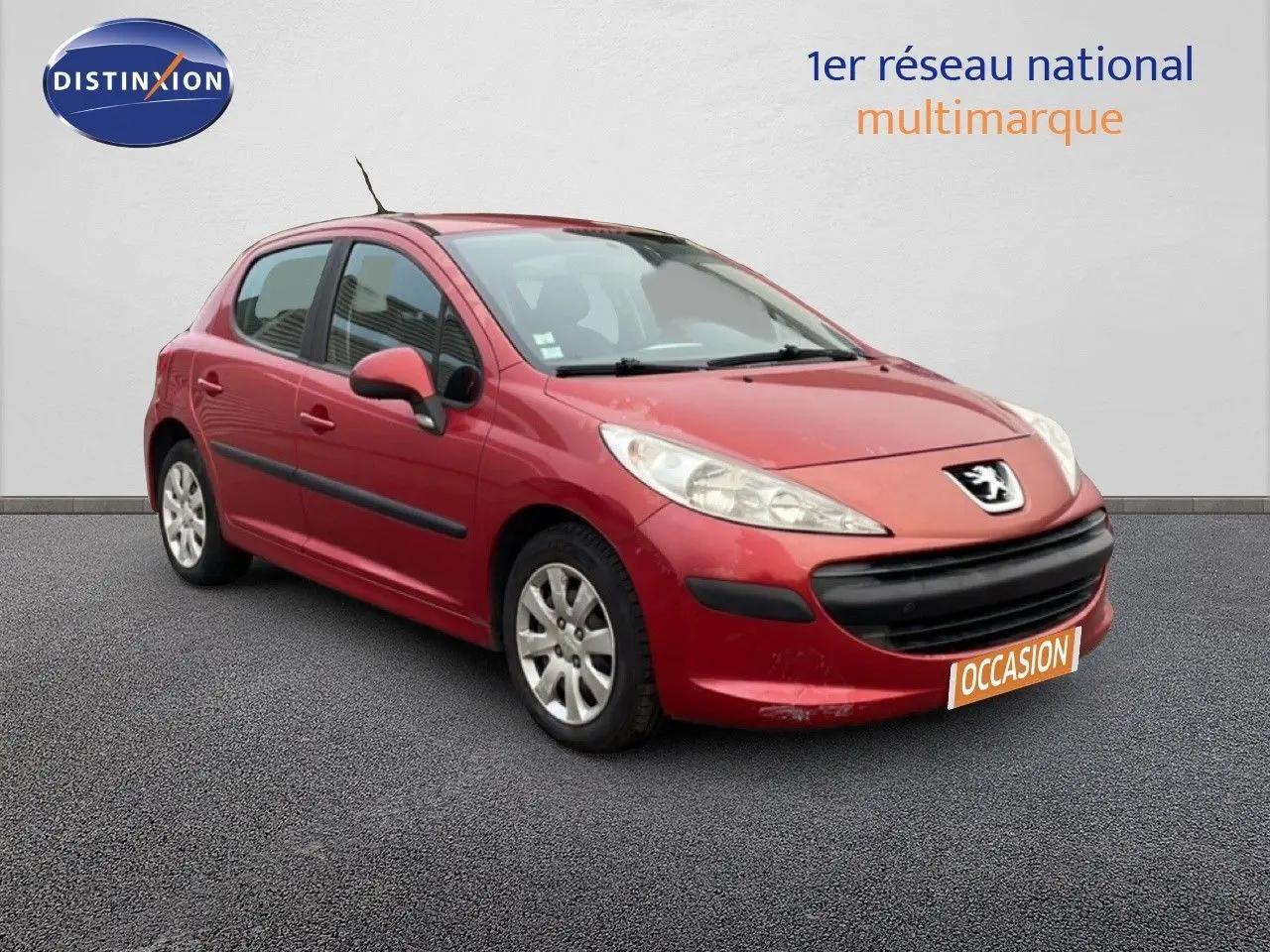 Peugeot 207 rouge métal vue 3/4 avant droit, compacte 5 portes avec pare-chocs noir et jantes alliage.