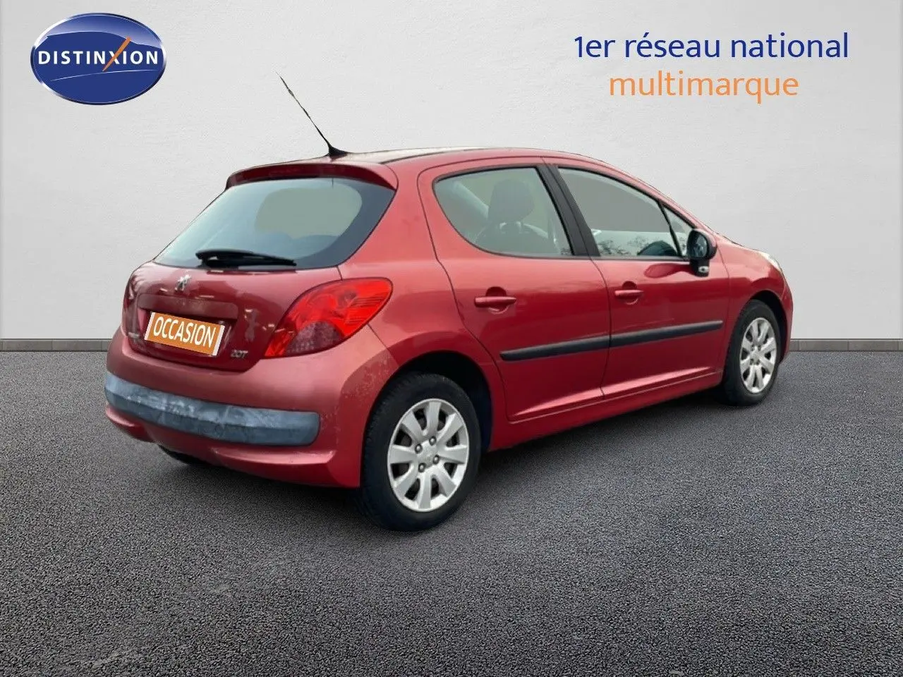 Peugeot 207 rouge métal vue 3/4 arrière côté droit, compacte 5 portes avec jantes alliage et antenne toit.