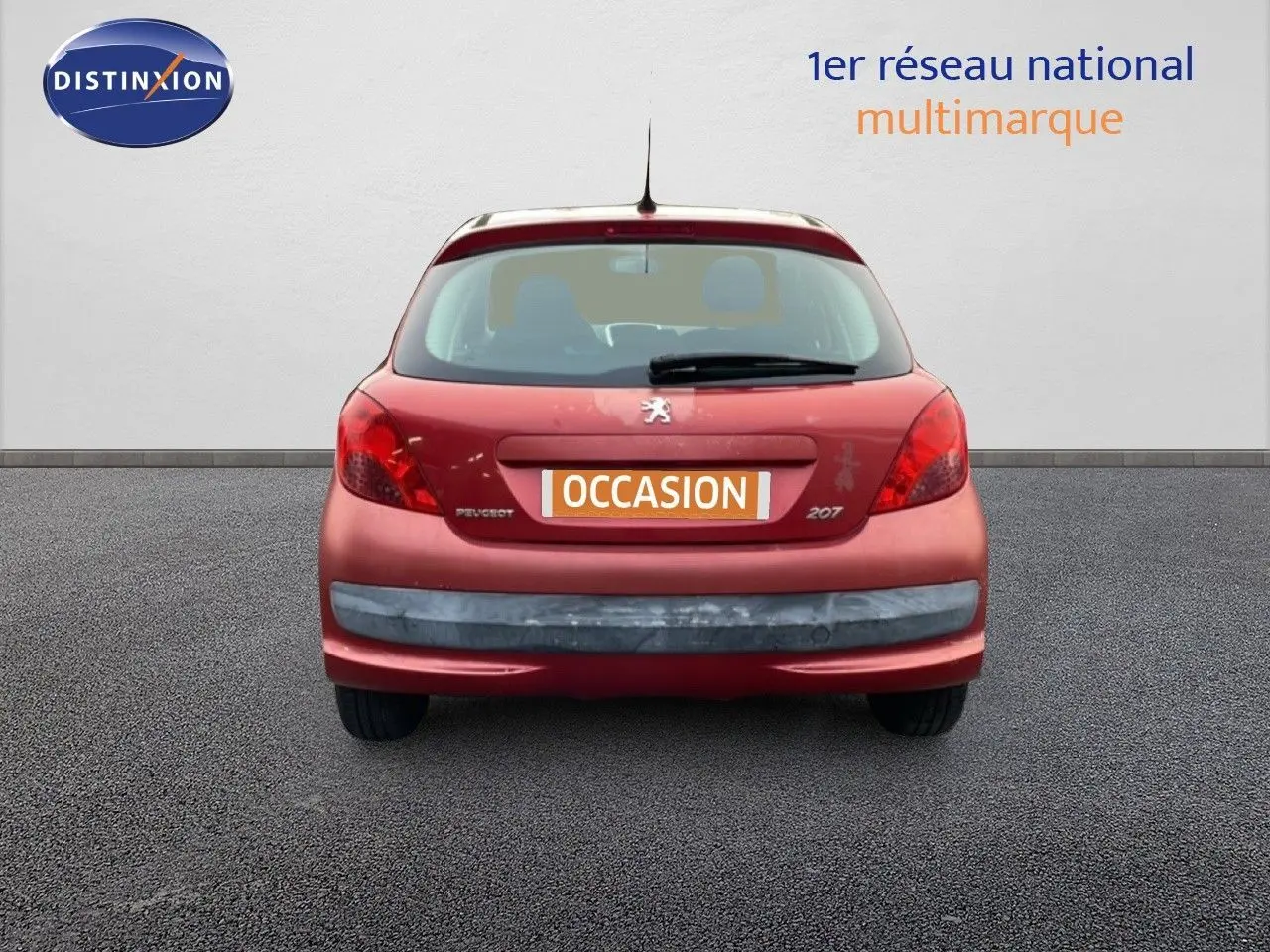 Vue arrière d'une Peugeot 207 rouge métal de 2009, compacte avec hayon et feux arrière rouges.