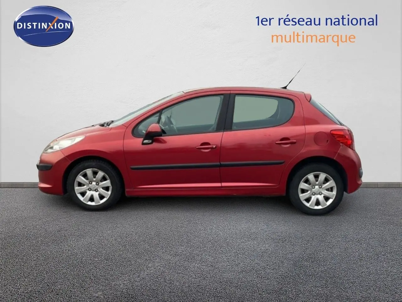 Profil côté gauche d'une Peugeot 207 rouge métal 5 portes de 2009, version HDI 70CH TREND avec jantes alliage.