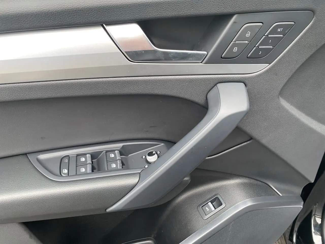Vue rapprochée de la porte avant gauche noire de l'Audi Q5 avec commandes de vitres, verrouillage et réglages mémoire.