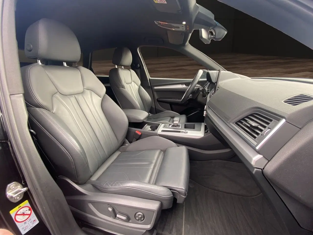 Vue intérieure côté gauche de l'Audi Q5 Business Edition S-Line 2022, sièges sport en cuir noir et tableau de bord moderne.