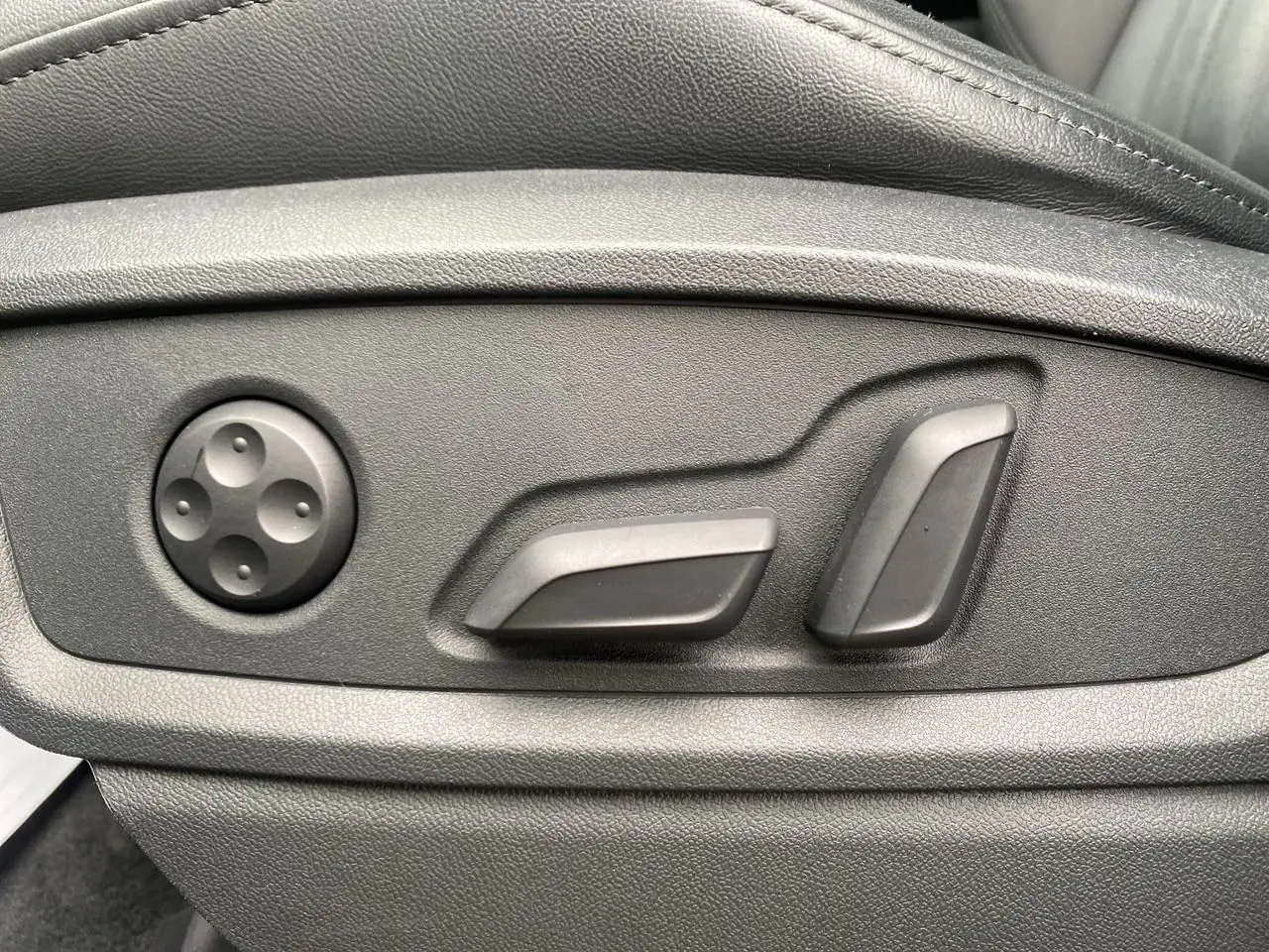 Gros plan sur les commandes électriques de réglage du siège avant côté gauche en cuir noir de l'Audi Q5 Business Edition 2022.