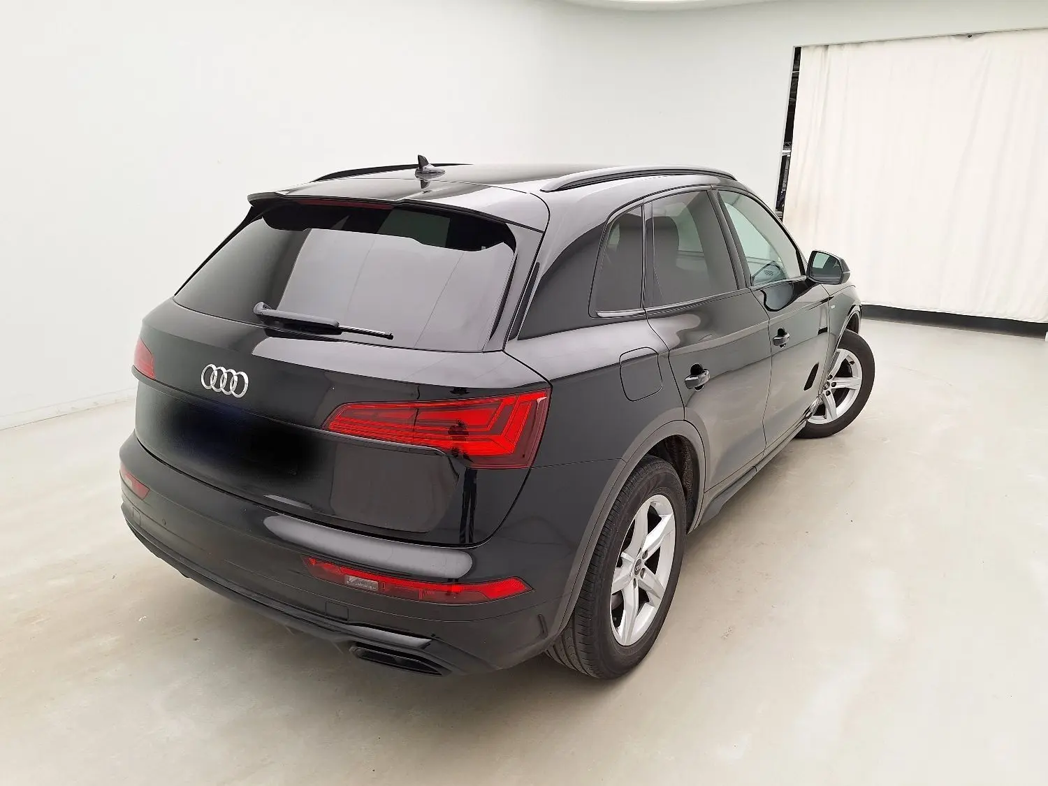 Audi Q5 noir vue 3/4 arrière droit dans un studio, mettant en valeur ses feux LED et son design élégant.