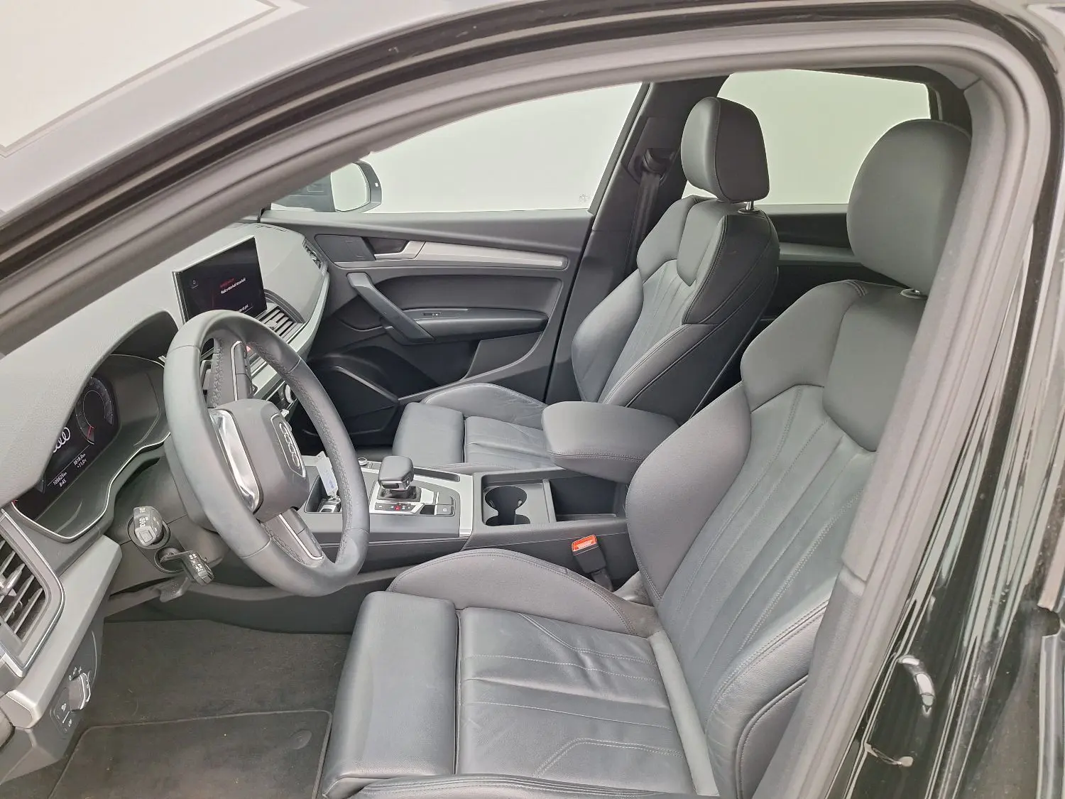 Vue intérieure côté gauche de l'Audi Q5 Business Edition S-Line noire, mettant en valeur les sièges sport en cuir et le tableau de bord digital.