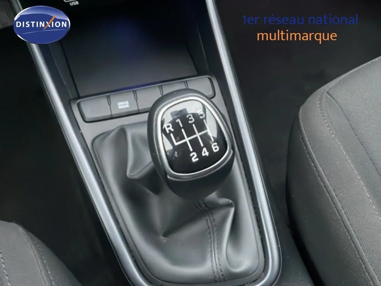 Gros plan sur le levier de vitesses manuel noir de la Hyundai i20 2025, intérieur tissu gris visible côté droit.