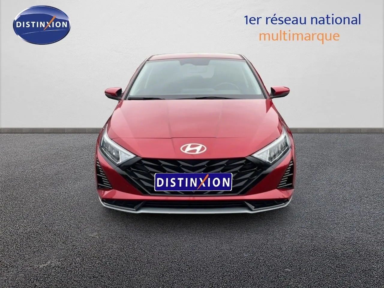 Vue frontale d'une Hyundai i20 2025 rouge Dragon Metal avec calandre noire et phares LED anguleux.