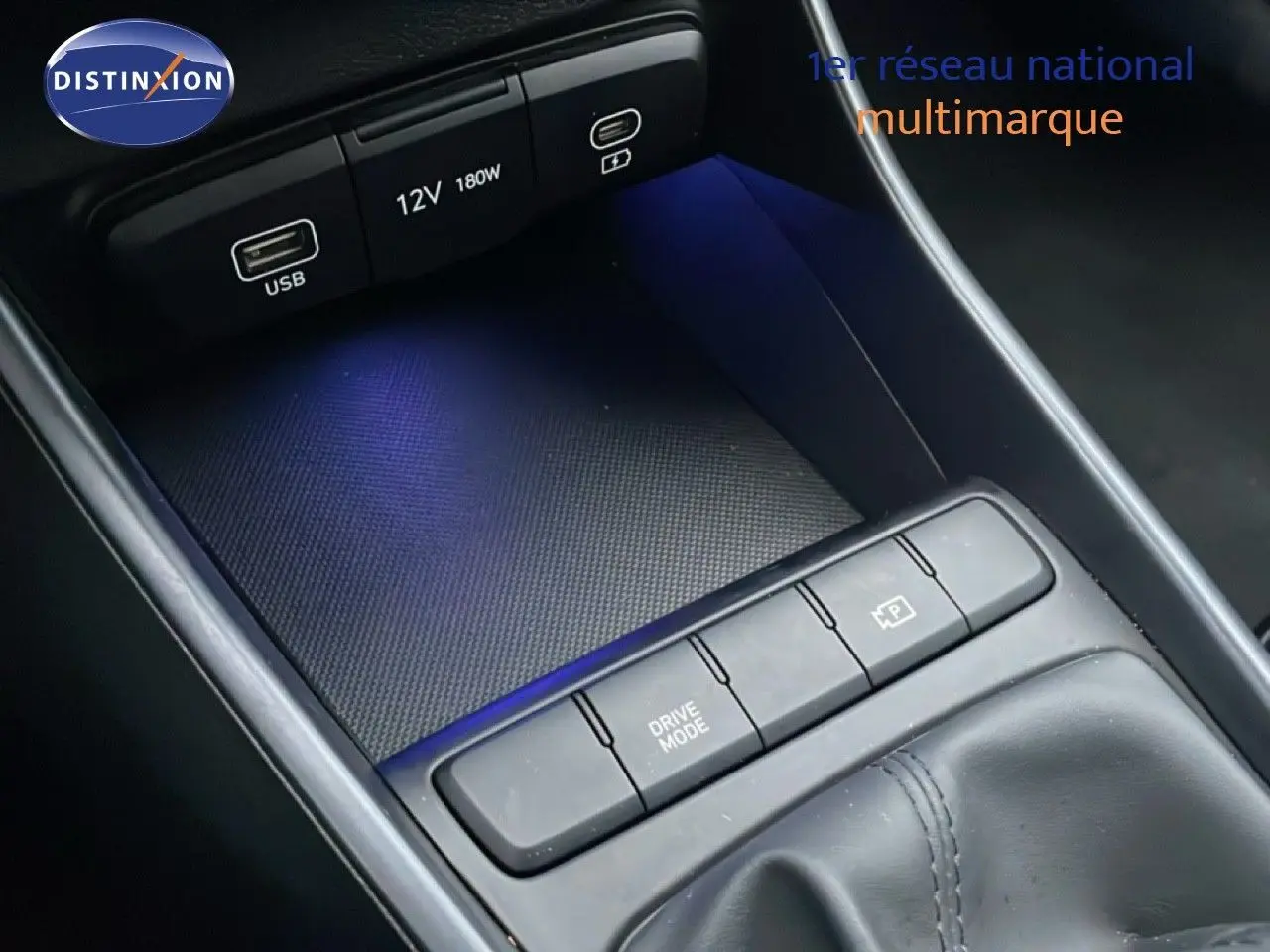 Gros plan sur la console centrale noire de la Hyundai i20 2025, avec boutons Drive Mode et prise USB visible.