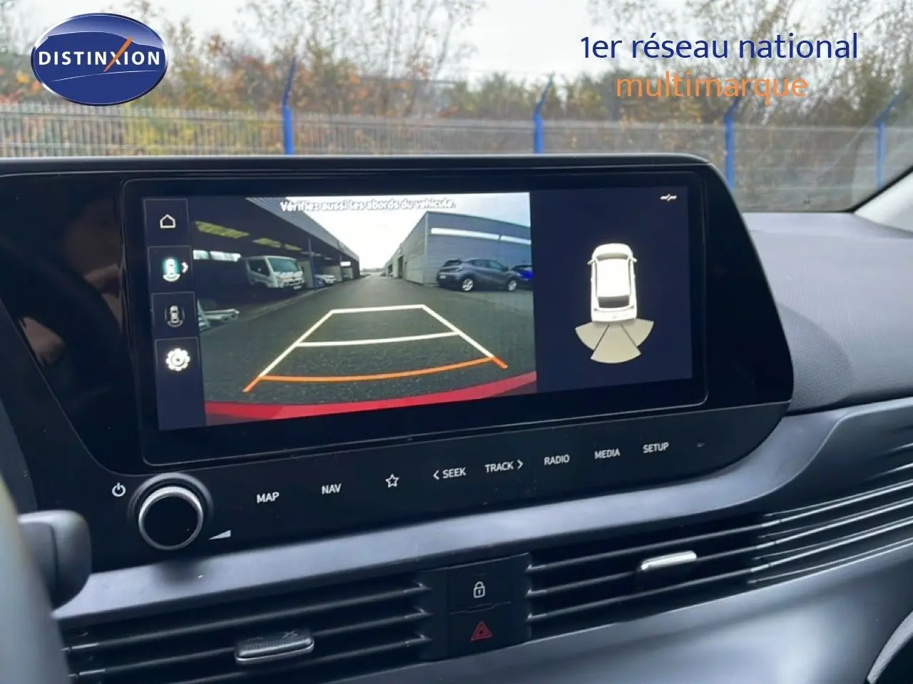 Écran tactile intérieur montrant la caméra de recul de la Hyundai i20 rouge Dragon Metal, vue du tableau de bord côté conducteur.