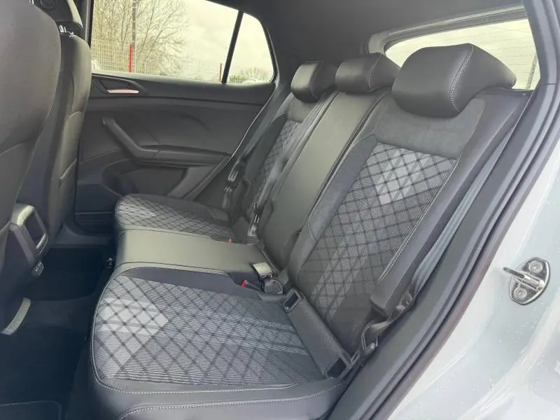 Vue intérieure côté droit des sièges arrière du Volkswagen T-Cross blanc pur 2025 avec sellerie tissu et cuir à motifs géométriques.