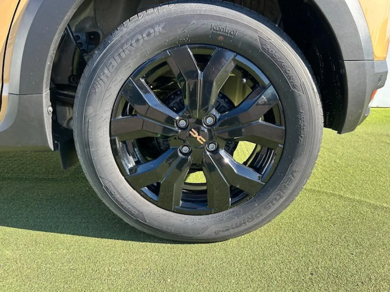 Gros plan sur la roue avant droite noire brillante du Dacia Sandero Stepway Beige Safari avec jante aluminium 16 pouces.