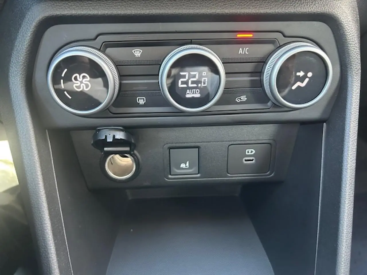 Gros plan sur la console centrale de la Dacia Sandero III Stepway, montrant les commandes de climatisation et prises USB.