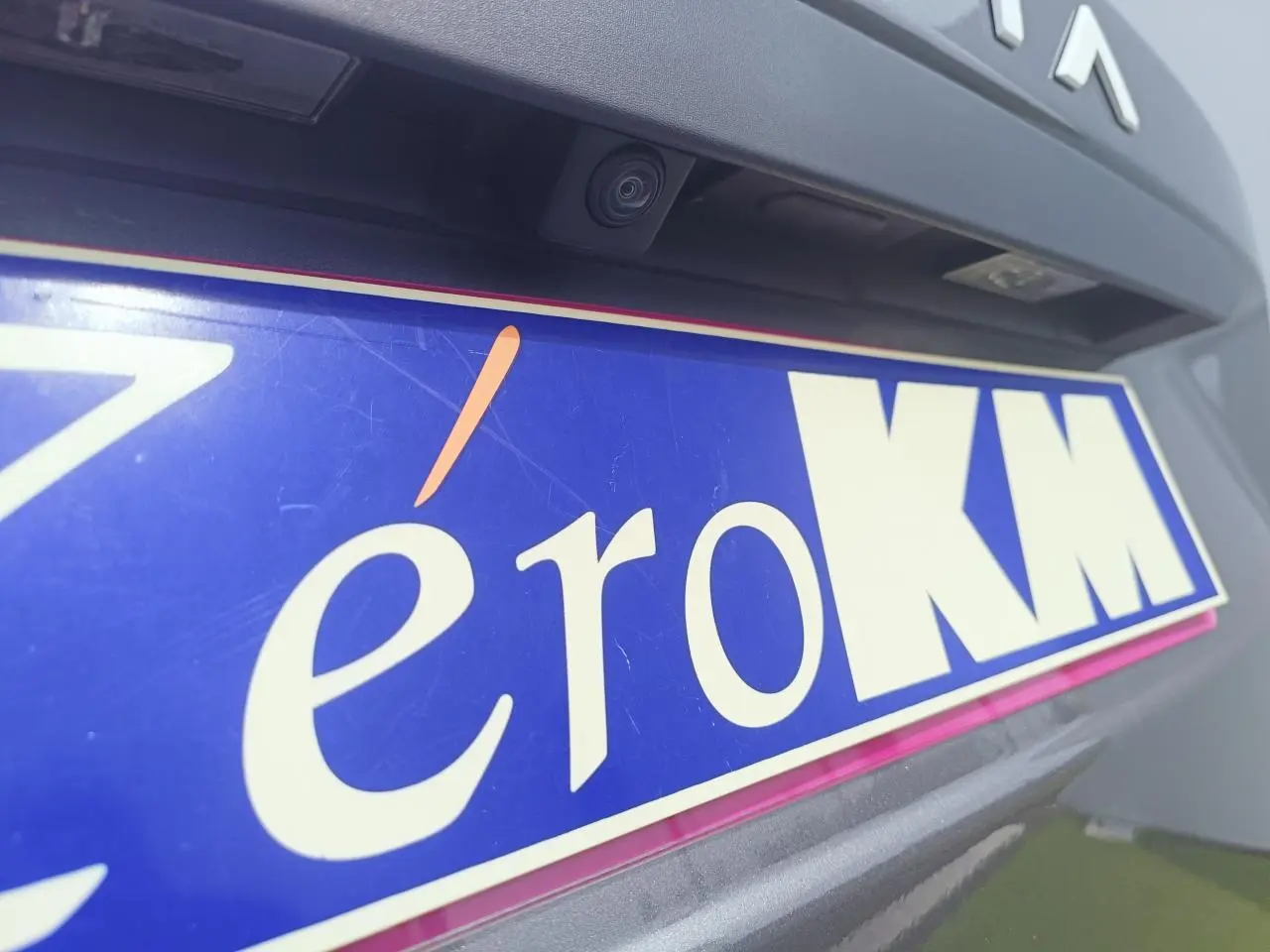 Gros plan sur la caméra de recul et la plaque d'immatriculation bleue d'un Dacia Duster gris schiste métal, arrière du véhicule.