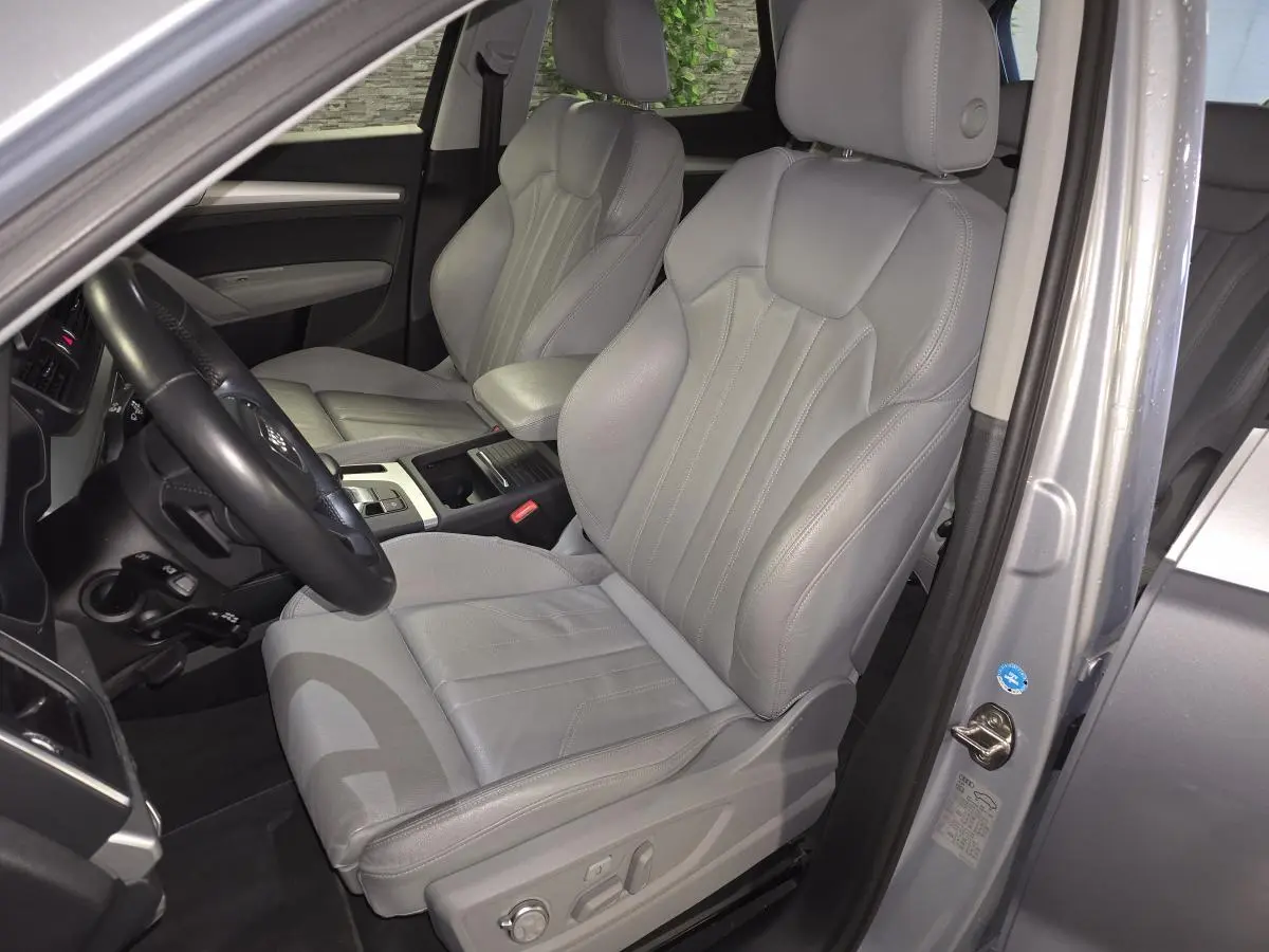 Vue intérieure côté conducteur de l'Audi Q5 gris, mettant en valeur la sellerie cuir Gris Roche et les sièges avant massants.