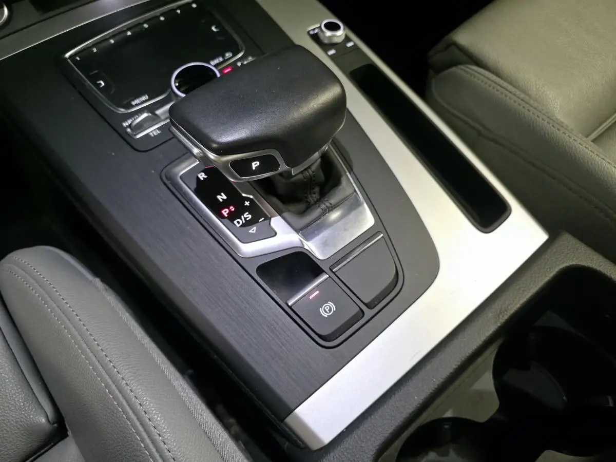 Gros plan sur la console centrale avec levier de vitesse automatique et sellerie cuir gris dans un Audi Q5 hybride rechargeable.