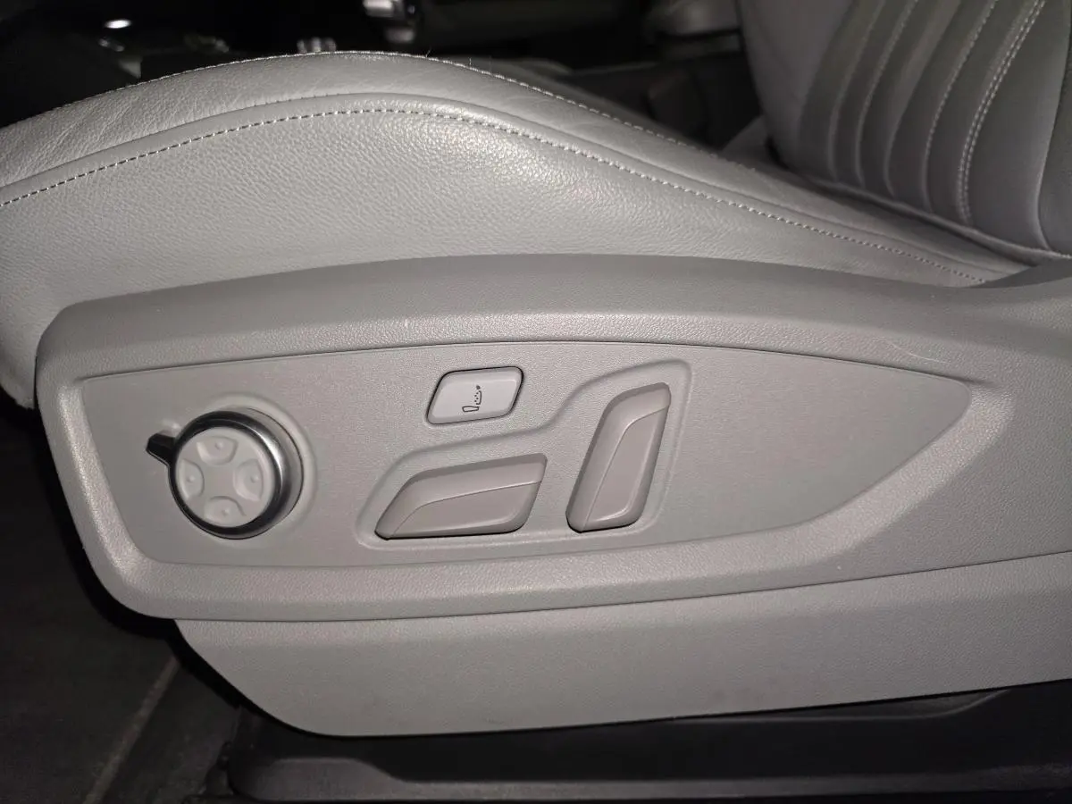 Gros plan sur les commandes électriques grises du siège avant conducteur en cuir gris de l'Audi Q5 S line.