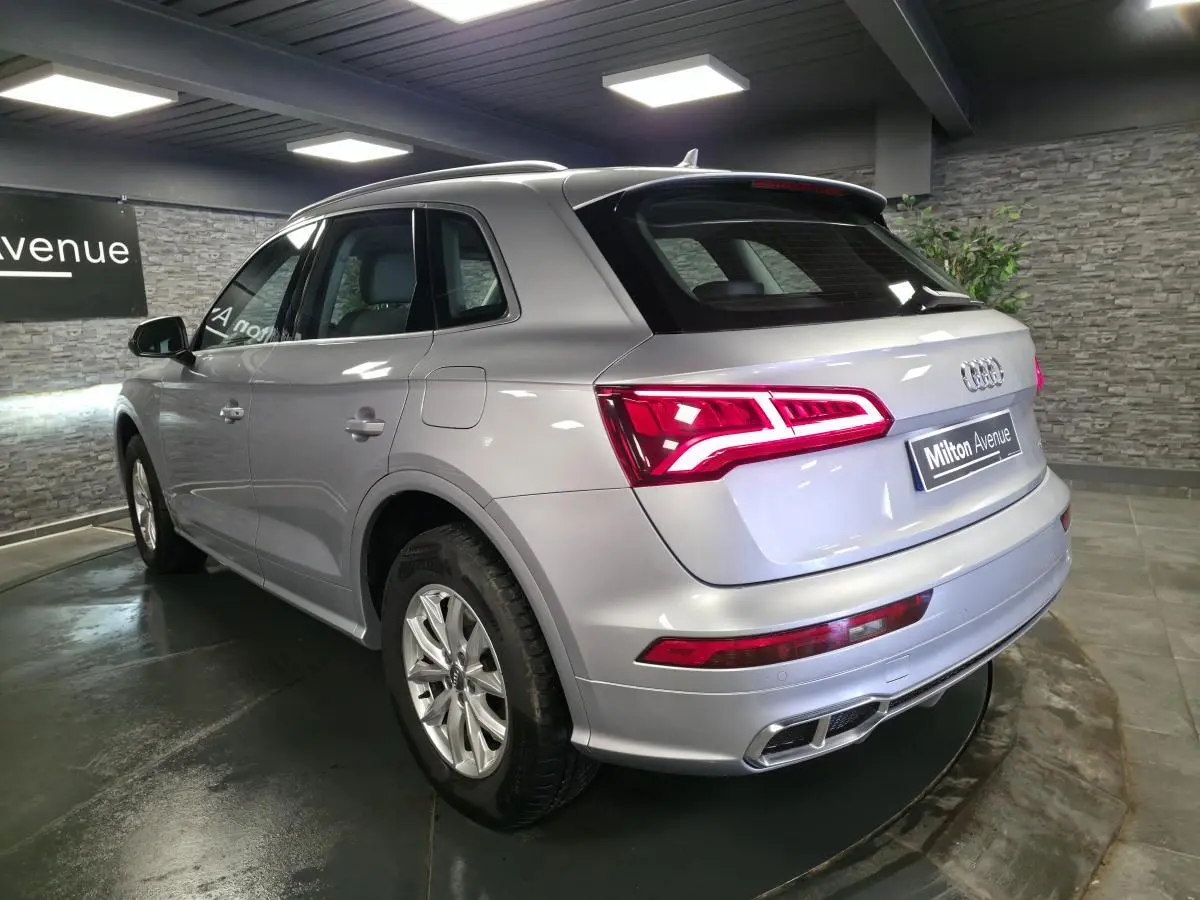 Audi Q5 gris en 3/4 arrière droit, avec feux LED allumés et jantes en aluminium 17 pouces.