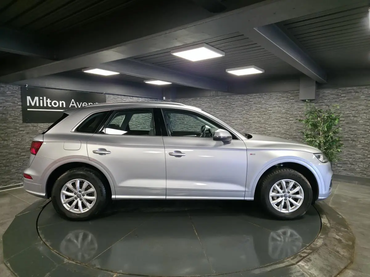 Audi Q5 gris en vue profil côté gauche, avec jantes en alliage et badge S line sur l'aile avant.