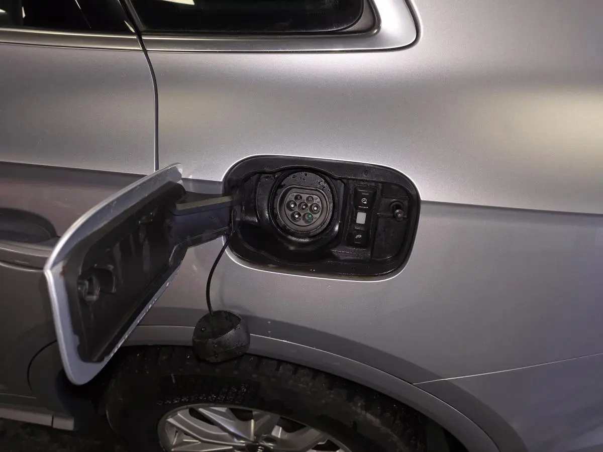 Détail de la trappe de recharge ouverte côté gauche sur Audi Q5 gris hybride rechargeable, avec prise visible.