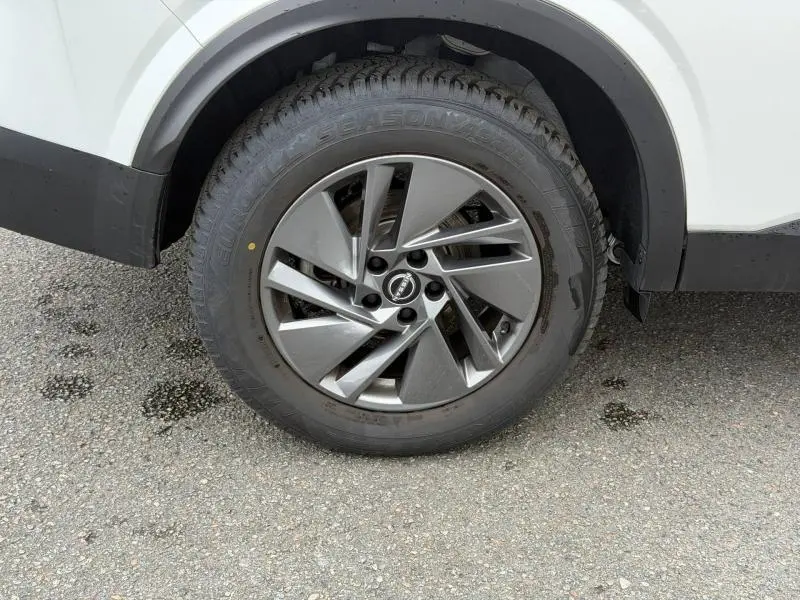 Gros plan sur la roue avant droite du Nissan Qashqai blanc nacré avec jante alliage au design moderne.