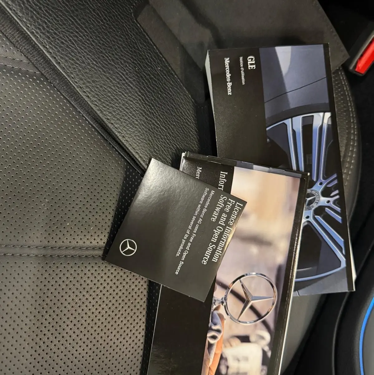Vue intérieure du siège en cuir noir perforé avec plusieurs brochures Mercedes-Benz posées dessus.