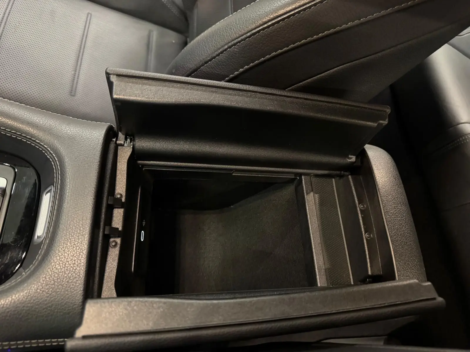 Vue rapprochée de la console centrale ouverte en cuir noir dans un Mercedes GLE 400 E Hybrid AMG Line 2023.