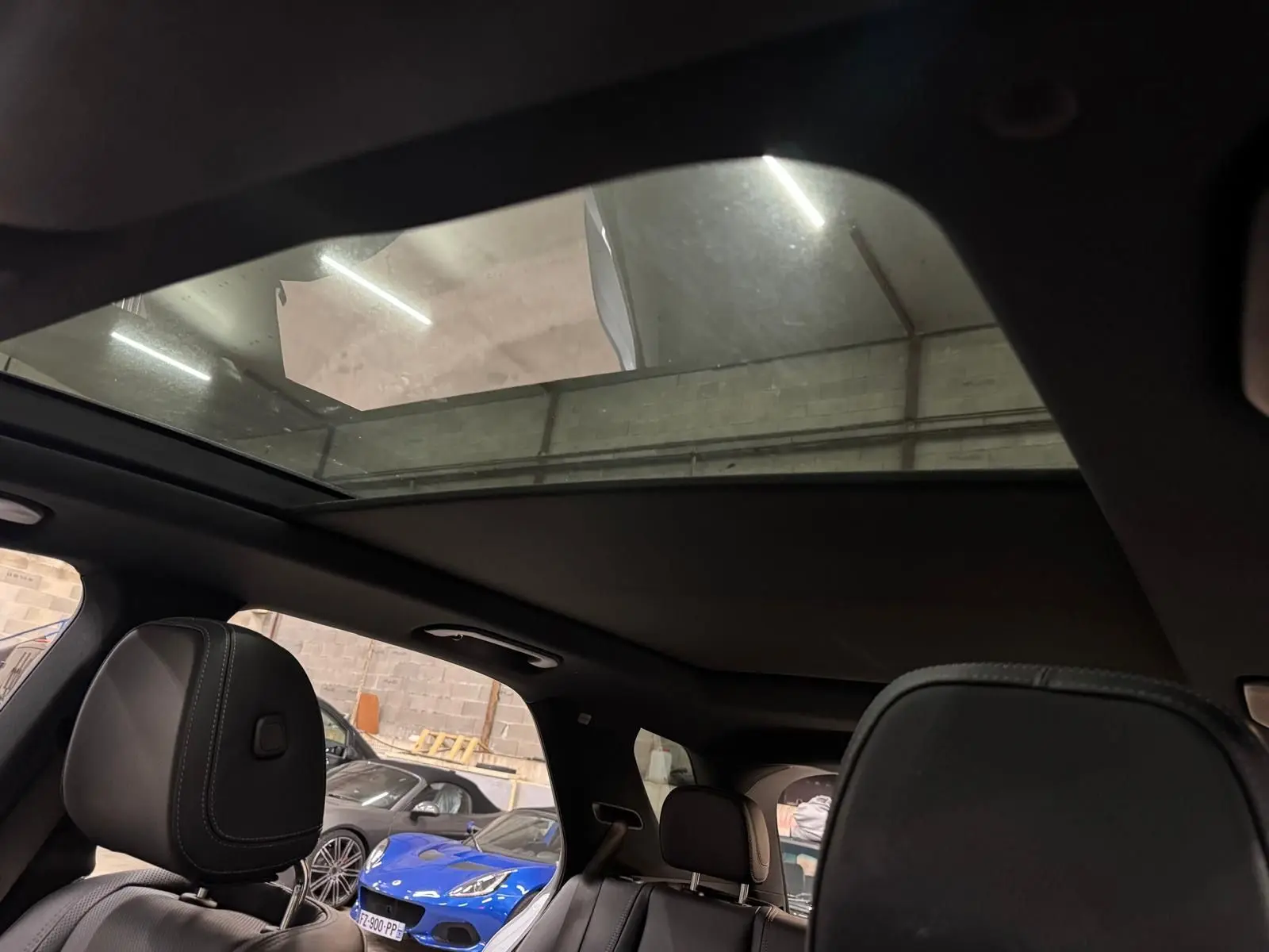 Vue intérieure du toit panoramique et des sièges noirs du Mercedes GLE 400 E Hybrid AMG Line 2023, avec lumière naturelle.