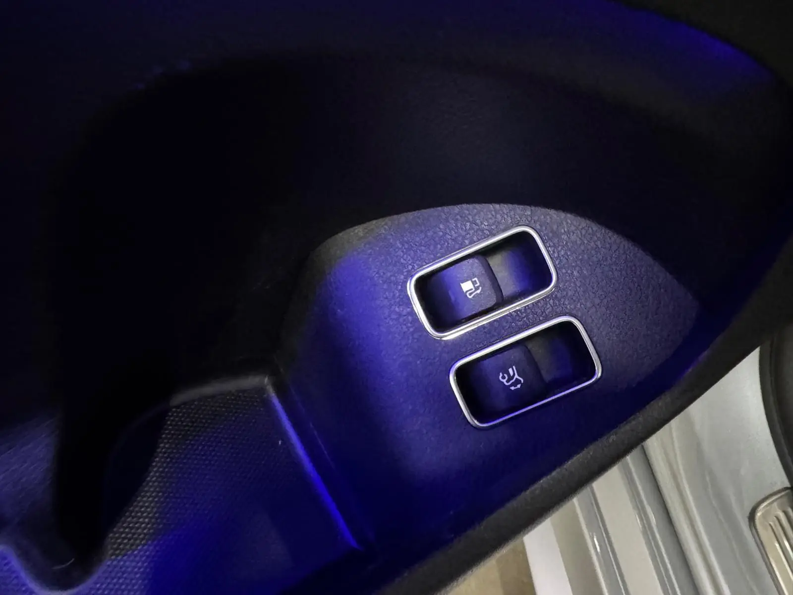 Gros plan sur les boutons d’ouverture du hayon et du coffre, intérieur noir du Mercedes GLE 400 E Hybrid argent.