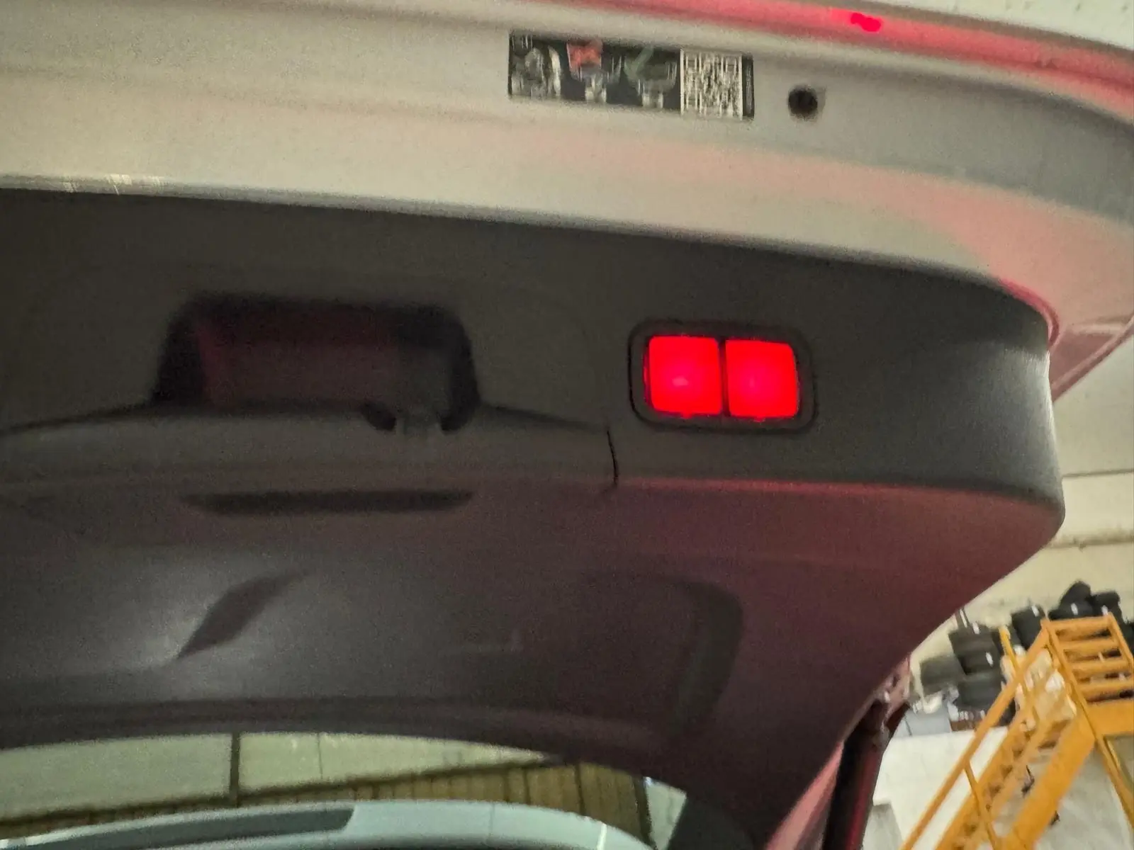 Vue en contre-plongée du hayon arrière ouvert d'un Mercedes GLE 400 E Hybrid AMG Line argent métallisé avec feux rouges intégrés.