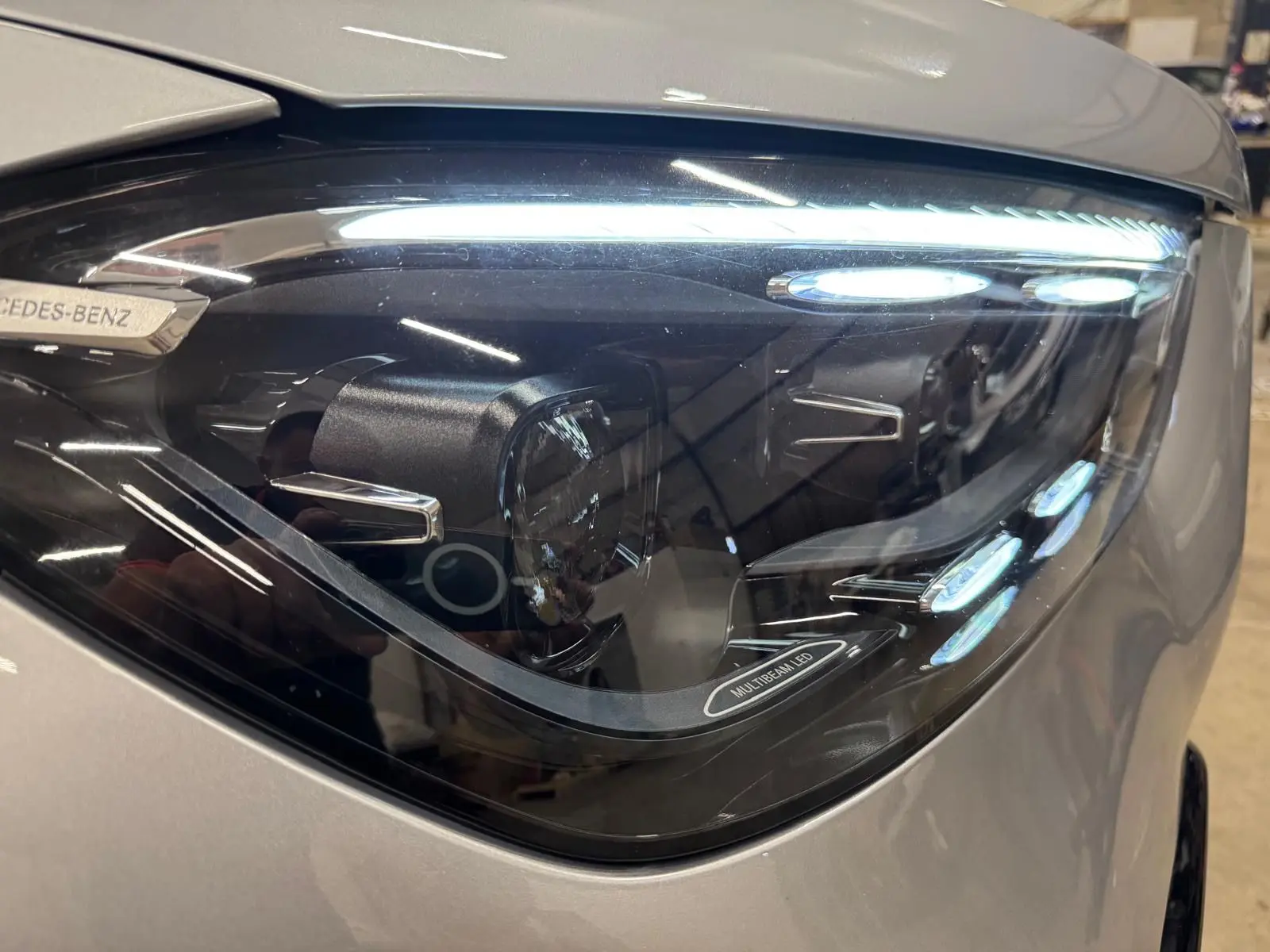 Gros plan sur le phare avant droit argent High-tech métallisé du Mercedes GLE 400 E HYBRID AMG LINE 2023 avec éclairage Multibeam LED.