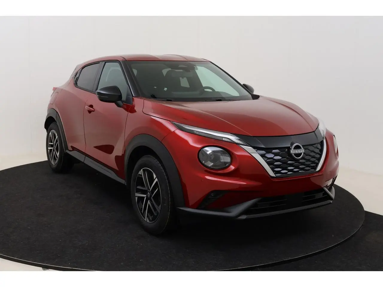 Nissan Juke 2026 rouge Fuji Sunset en 3/4 avant droit, avec calandre noire et jantes alliage 17 pouces.
