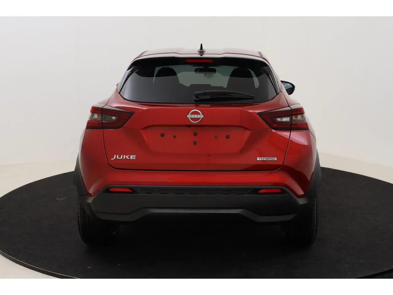 Vue arrière d'un Nissan Juke 1.6 Hybrid rouge Fuji Sunset avec logo et feux arrière distinctifs.
