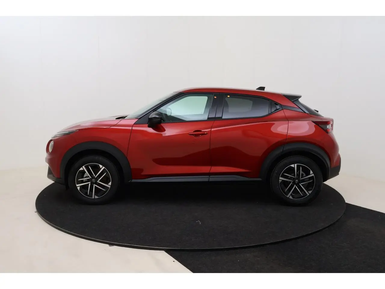 Nissan Juke rouge Fuji Sunset vue de profil côté gauche, jantes alliage 17 pouces et lignes dynamiques marquées.