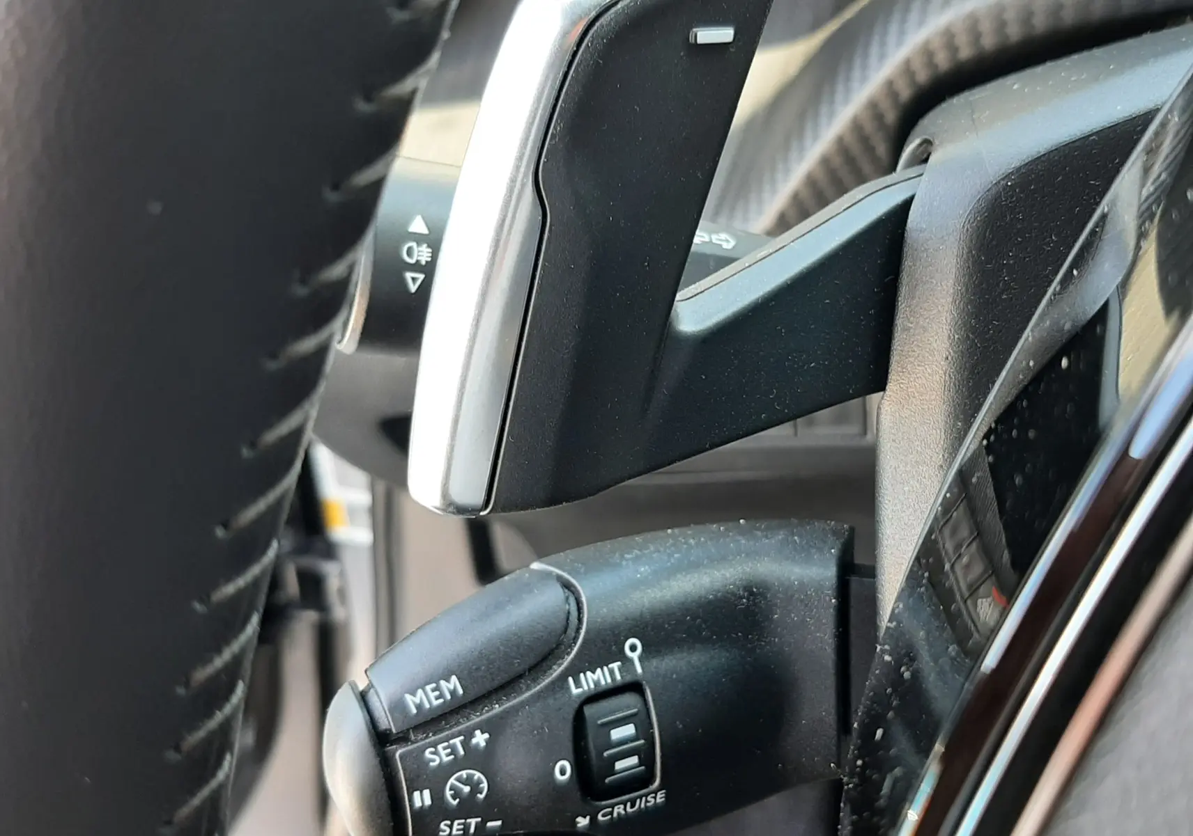 Gros plan sur la commande de régulateur de vitesse et palette de boîte automatique dans le volant noir du Peugeot 2008 gris platinium.