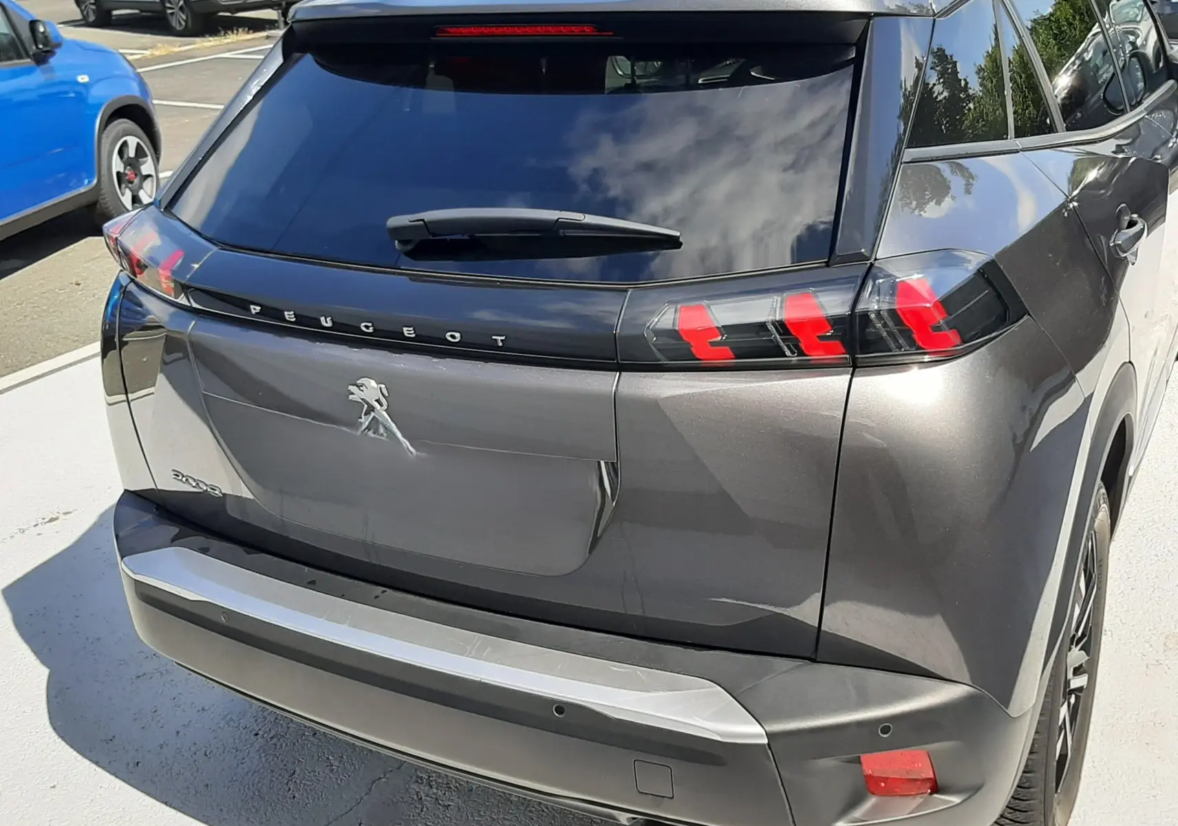 Vue arrière droite d'un Peugeot 2008 gris platinium 2023 avec feux arrière LED caractéristiques et toit noir.