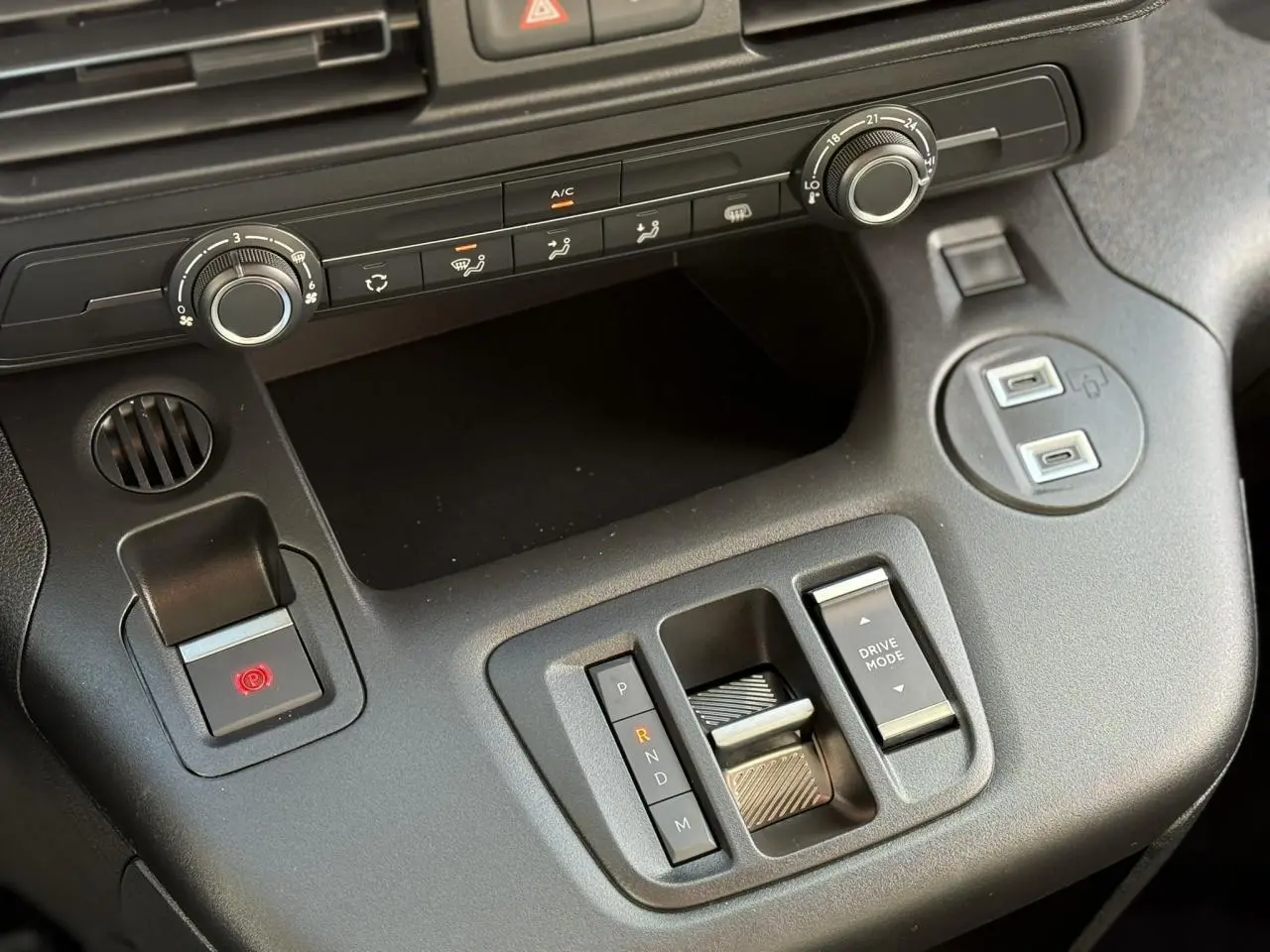 Gros plan sur la console centrale noire du Citroën Berlingo 2025 avec commandes de climatisation et levier de boîte automatique.
