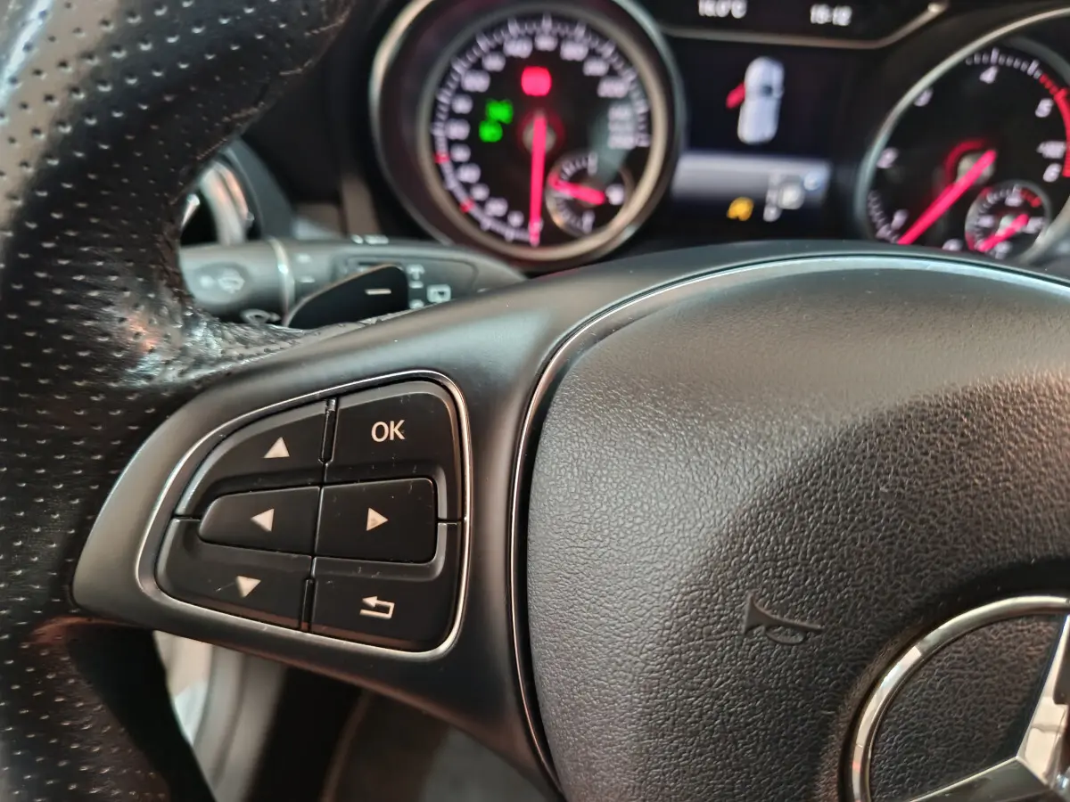 Gros plan sur le volant cuir noir de la Mercedes GLA 200 d 2018 avec commandes multifonctions et tableau de bord lumineux.