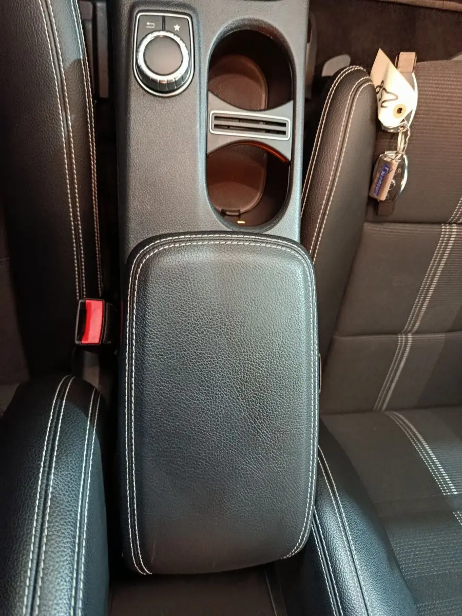 Vue plongeante sur la console centrale en cuir noir avec coutures blanches et siège tissu gris du Mercedes GLA 200 d 2018.