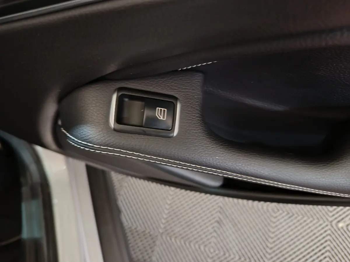 Bouton de commande de lève-vitre sur la porte côté gauche en cuir noir avec surpiqûres blanches d'une Mercedes GLA gris clair 2018.