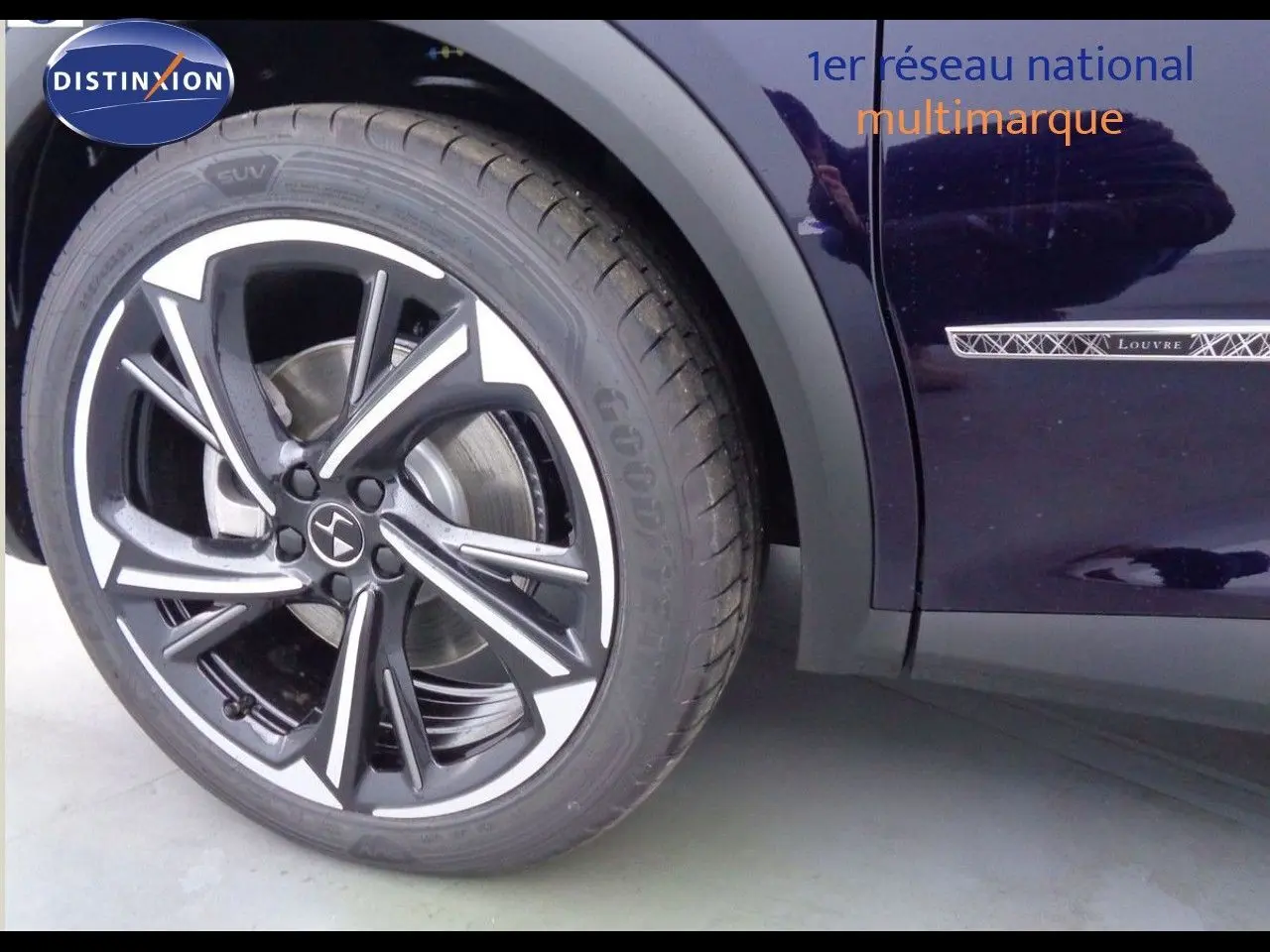 Gros plan sur la roue avant gauche et la porte côté gauche d’un DS7 Crossback Bleu Encre Métal avec badge Louvre.