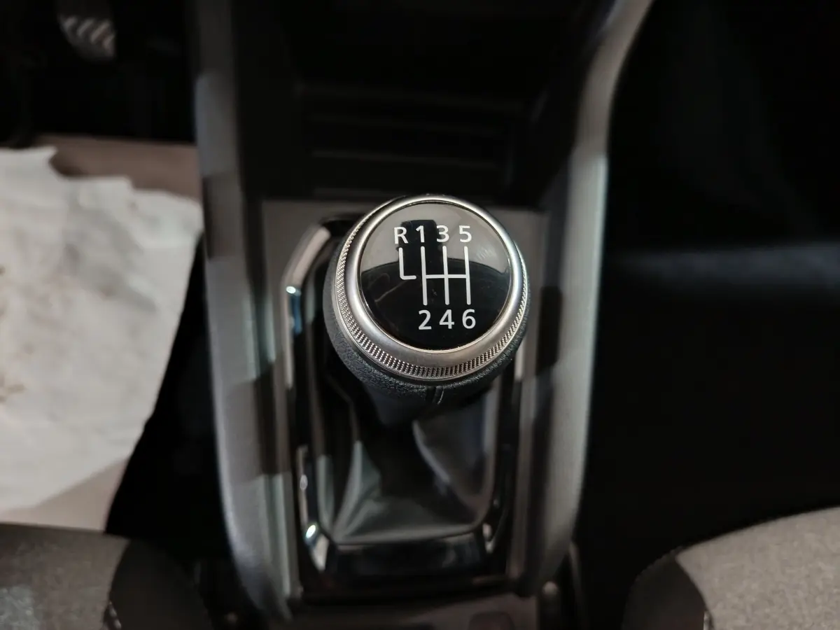 Le levier de vitesses manuel noir de la Renault Clio gris clair, vu en gros plan depuis le dessus.