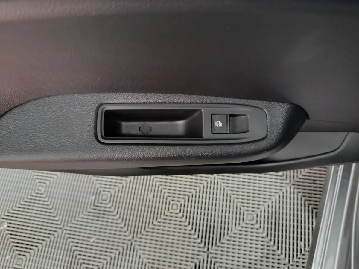 Gros plan sur la poignée intérieure de porte côté droit de la Renault Clio gris clair, avec bouton de verrouillage.