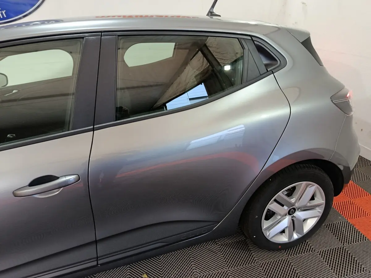 Vue latérale droite sur l'arrière d'une Renault Clio gris clair, mettant en valeur la ligne fluide et la jante alliage.