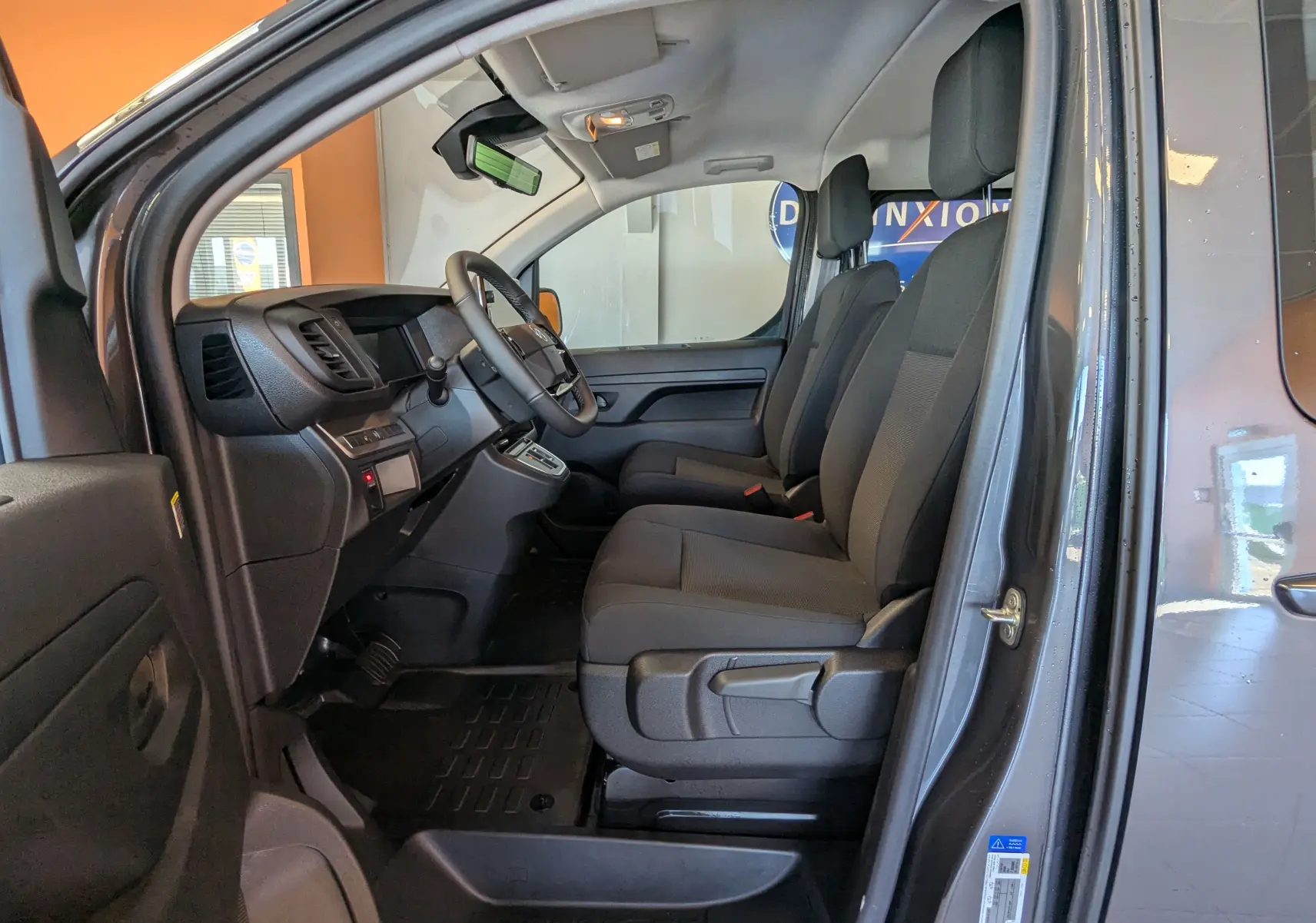 Vue intérieure côté conducteur du Citroën Jumpy Cabine Approfondie gris titane, montrant les sièges avant et le tableau de bord.